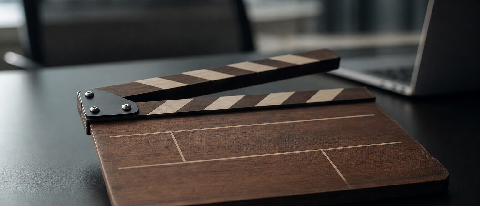 A close-up of a film clapperboard with a subtle digital overlay effect, symbolizing the intersection of traditional media control and AI regulation.
