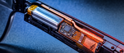 Close-up of a smart glasses temple interior, showing a tiny chip module and thin battery with thermal heat-map colors