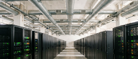 A nearly empty AI compute center hall with rows of dark server cabinets, only a few powered on, under cool blue lighting.