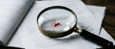 Magnifying glass revealing red cracks on audit report.