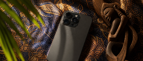 A modern smartphone resting on traditional Southeast Asian Batik fabric with tropical lighting.