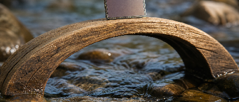 A delicate mobile phone chip die balanced on a wooden arch bridge over a flowing stream, symbolizing memory bandwidth and sustained workload.
