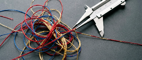 A conceptual editorial image showing a complex, tangled knot of colorful threads being systematically untied by a precise, geometric tool, symbolizing the resol