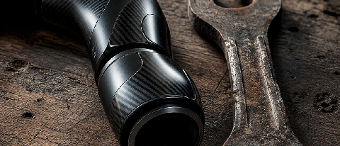 A close-up editorial shot of a sleek, dark robotic arm joint resting next to a weathered, rusty wrench on a dusty industrial workbench, symbolizing the disconne
