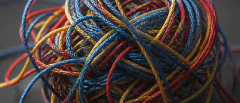 A tangled knot of colorful threads representing complex, invisible code dependencies.
