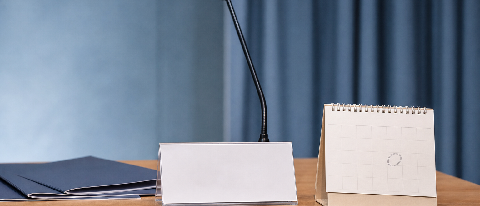 An empty product launch stage with a single blank placard and a calendar page turned to June 26.