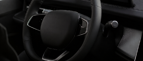 A symbolic editorial image showing a hand reaching out to touch a sleek, modern car dashboard, representing the transfer of control and liability.