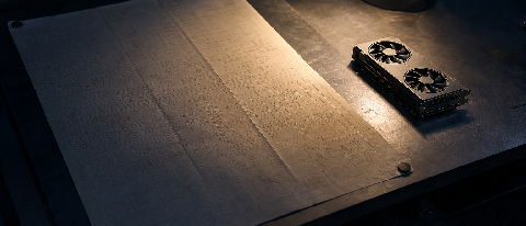 Editorial still life of consumer GPU beside an oversized blueprint block, symbolizing the gap between model parameters and real-world deployment capacity.