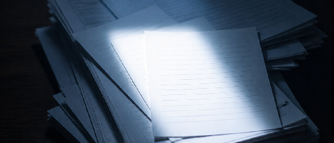 A precise beam of light filtering through a dense stack of documents