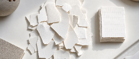 A conceptual editorial image showing fragmented document pages being organized into neat, structured stacks under soft studio lighting.