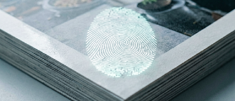 A conceptual editorial image showing a digital fingerprint being embedded into a stack of film reels or photo prints, symbolizing proof of authorship.