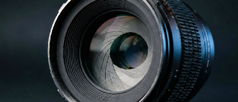 A close-up of a professional cinema lens focused on a reflective surface, symbolizing precision and optical control.