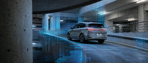 Electric SUV driving up a curved ramp in a concrete parking garage with a faint blue grid overlay representing 3D occupancy data.