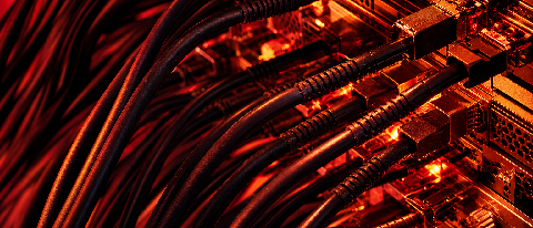 A close-up editorial shot of a complex, overheating server rack with glowing red heat indicators and tangled cables, symbolizing the high cost and thermal manag