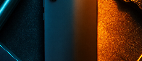 A sleek smartphone on a dark matte surface with split cool blue and warm amber lighting.