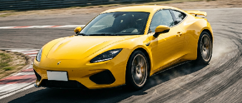 A dynamic editorial shot of a yellow sports car navigating a sharp turn on a sunlit racetrack, emphasizing motion and technical precision.