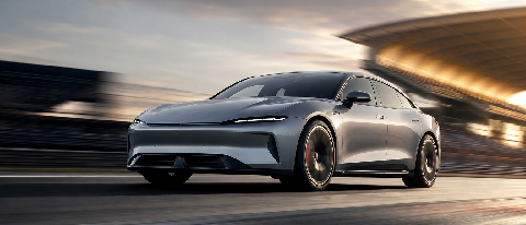 A sleek, high-performance electric sedan in motion on a modern track