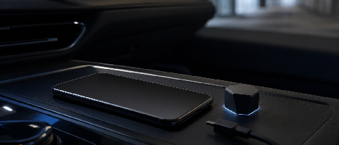 A minimalist editorial still life showing a sleek smartphone resting on a dark dashboard surface next to a small, disconnected potted plant, symbolizing local v