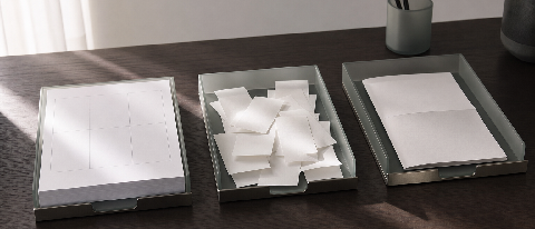 An editorial photograph showing three neatly organized, minimalist document trays on a modern office desk, symbolizing a structured three-step workflow.
