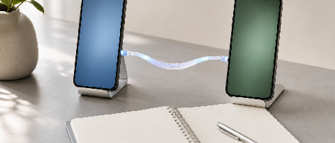 Editorial still life of two smartphones on a desk connected by a glowing fiber-optic cable, with a neatly organized weekly report notebook.