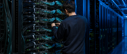 A large server rack in a data center with a technician inspecting connections