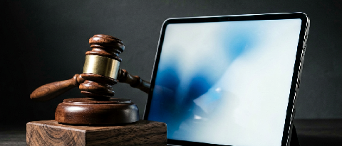 A gavel striking a block next to a blurred digital interface, symbolizing legal enforcement against AI