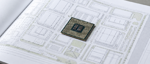 A conceptual editorial image showing a sleek, minimalist AI chip resting on a blueprint of a smart city district, symbolizing the shift from hardware specs to r