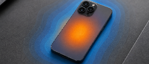 A close-up editorial shot of a smartphone lying next to a thermal imaging overlay visualization, symbolizing heat management and performance testing.