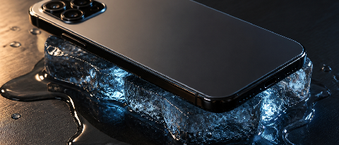 Editorial photo of a slim smartphone on a dark surface with a melting ice cube beneath it, symbolizing hidden thermal costs of on-device AI.