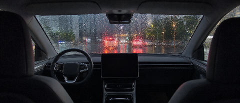 Driverless robotaxi driving through heavy summer rain on a wet urban street