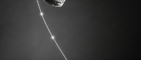 A glass cup frozen in mid-air falling toward a grid-patterned floor with a trajectory line.